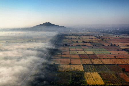 Dawn looking towards Mandalay hill. with fog on the left, and rice paddy fields on the right. The photo was taken from a hot air balloon. Mandalay, Myanmar, travel, landscape, dawn, fog, hill.